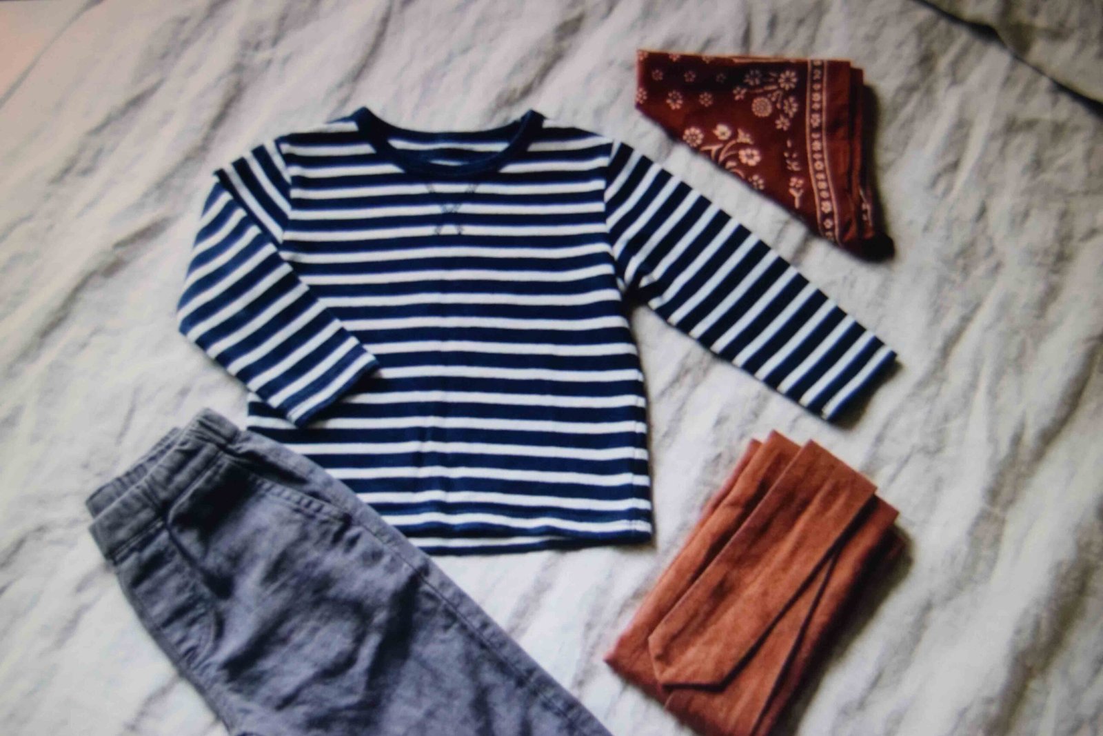 A child sized striped top trousers sash and bandana laid out together