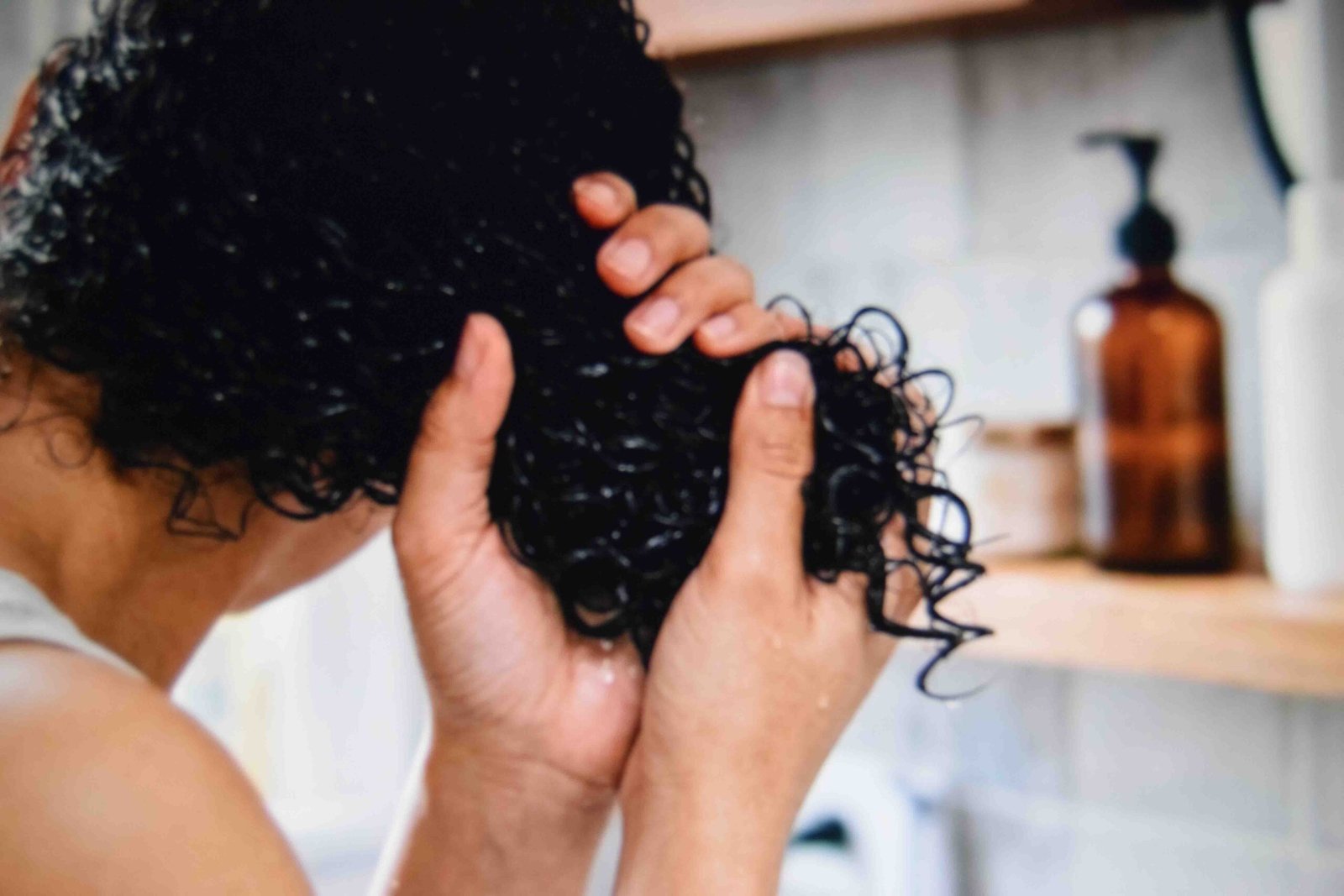Hands scrunching wet curls upward to build definition without product