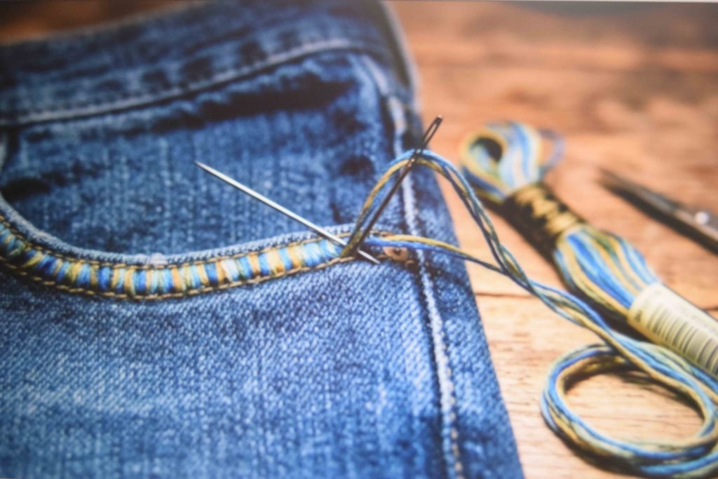 Embroidery floss stitched around a denim pocket outline for raised texture