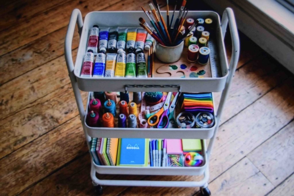 A three tier rolling cart with color coded tiers for homeschool cart organization