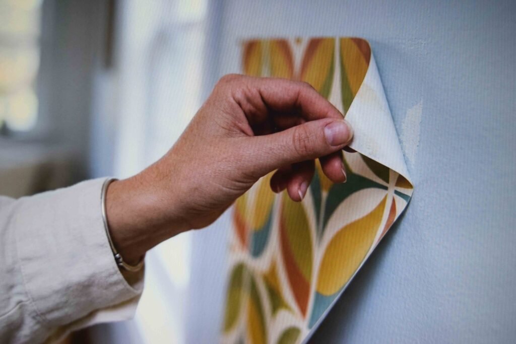 A peel and stick wallpaper sample being lifted from a wall to check that it removes cleanly