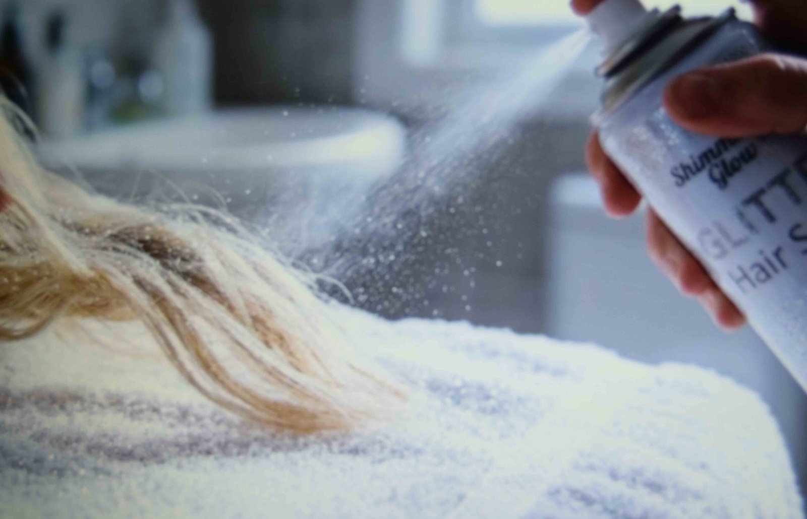 Pink glitter hair spray applied to the ends of blonde hair over a towel