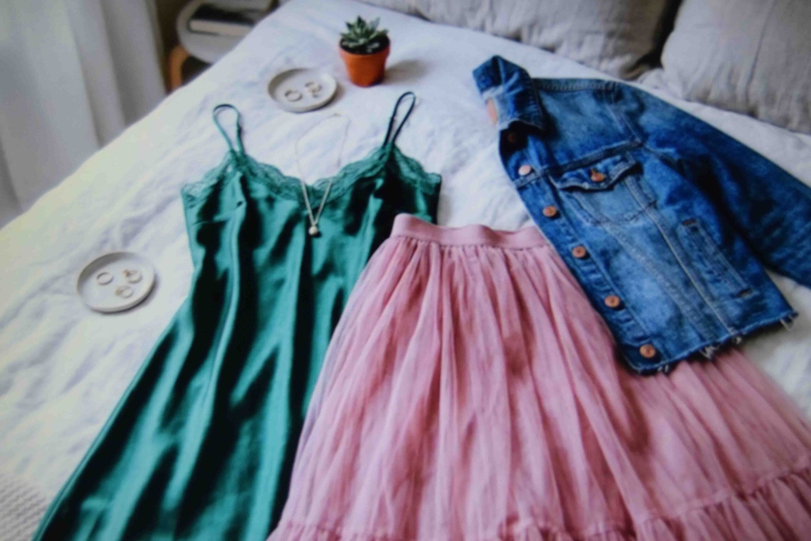 A slip dress tulle skirt and denim jacket laid out as bases for a pink hair look