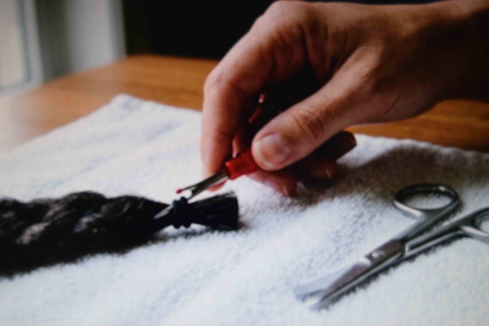A seam ripper being slid under a band to cut it away from a braid