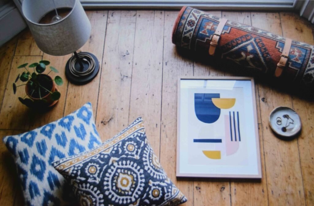 Four starter pieces of retro apartment decor laid out on a bare floor before furniture is bought