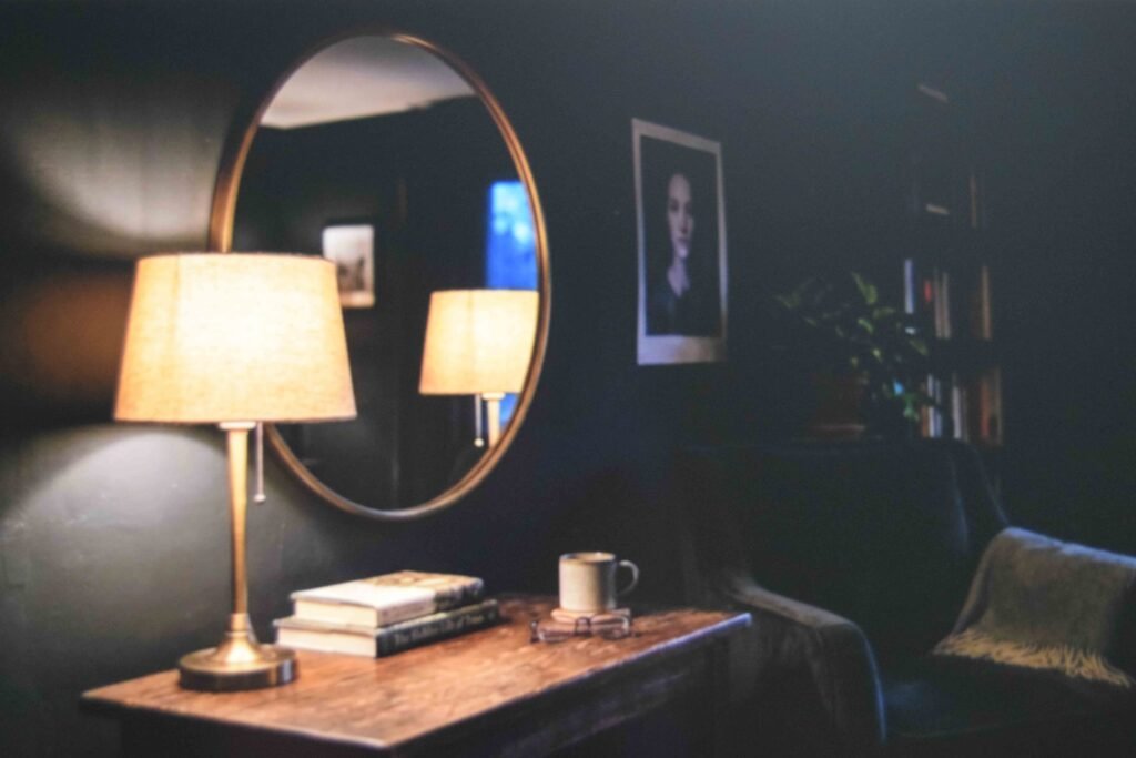 A warm table lamp placed beside a round mirror so the evening glow reflects into the room