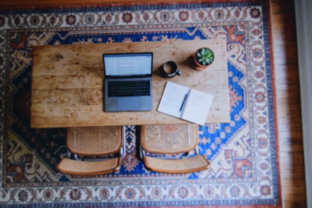 A patterned low pile rug under a work table to soften noise from two children working