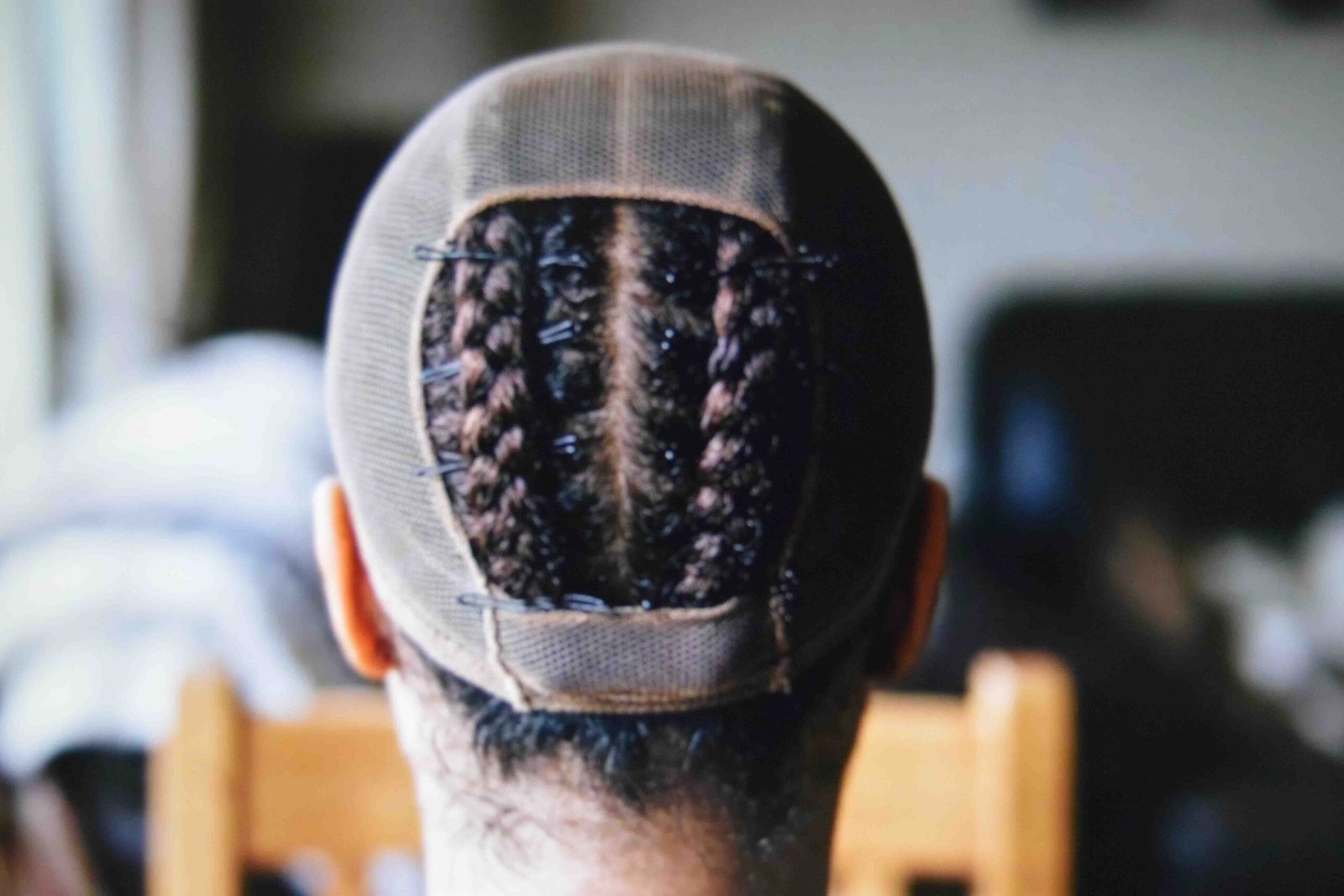 Braids pinned under a mesh cap so the wig grips instead of sliding