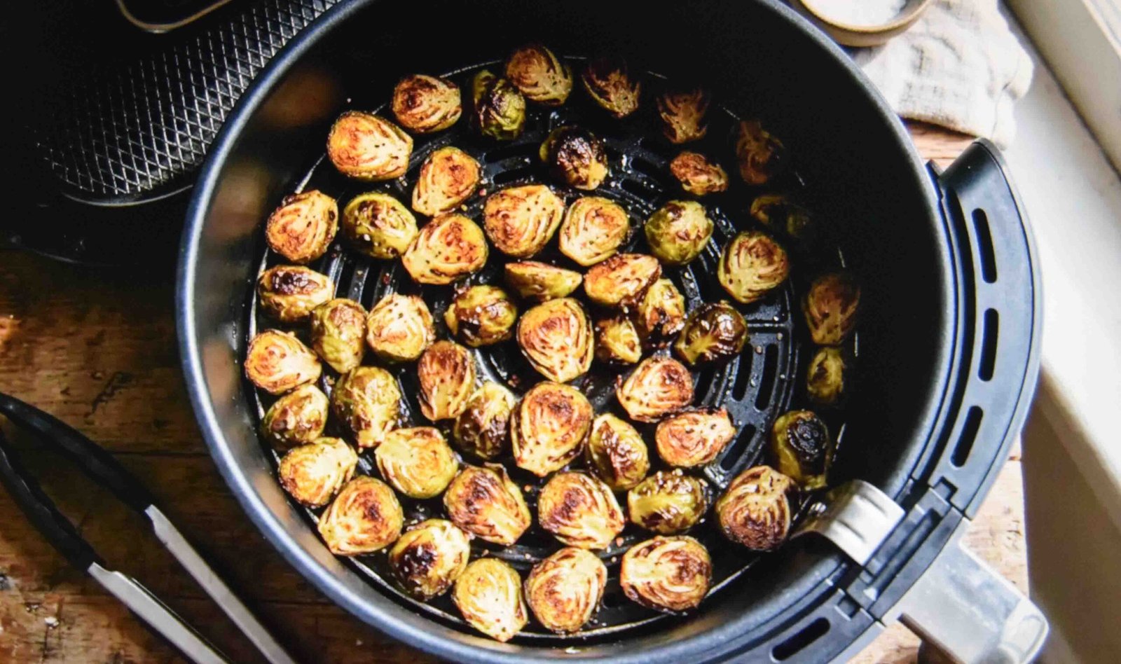Halved brussels sprouts crisping alongside a chicken cook in the air fryer