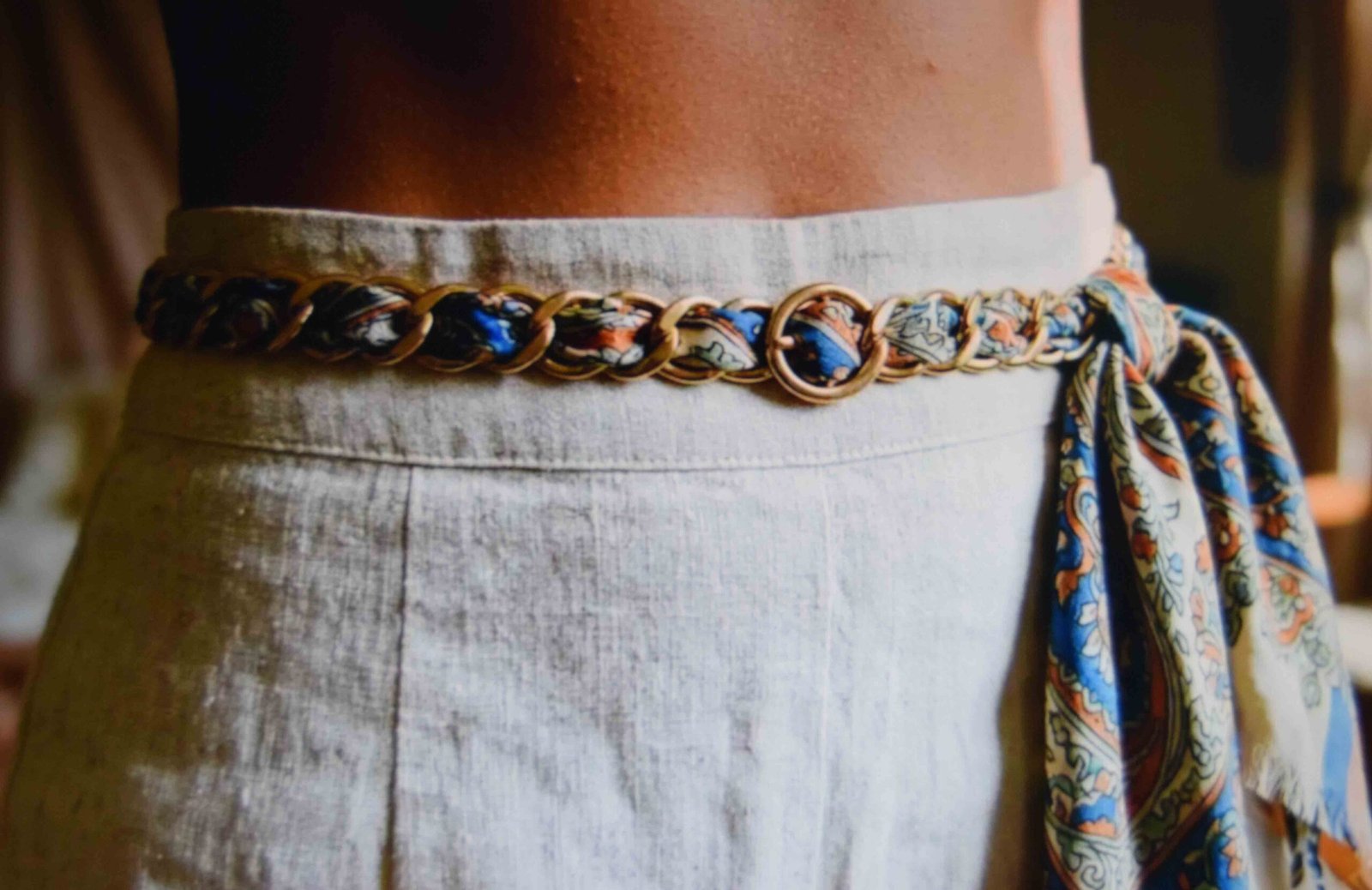 Silk scarf woven through the links of a thin chain belt with a loose end at the hip