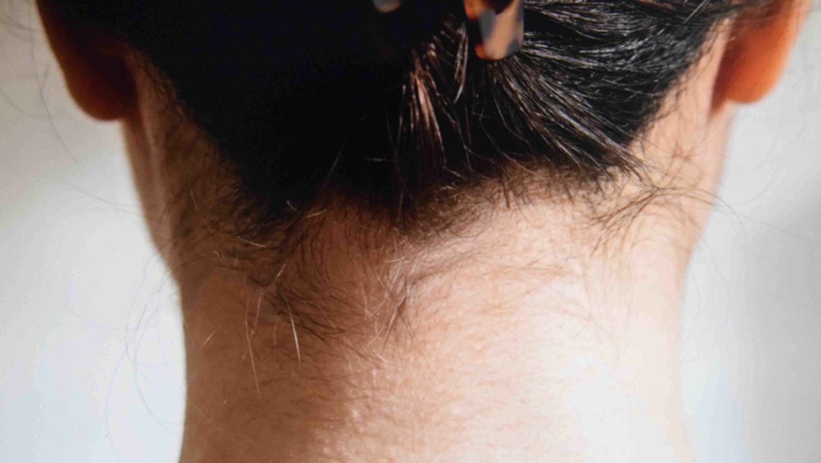 Close view of a claw clip sitting an inch above the nape with an enclosed hinge underside