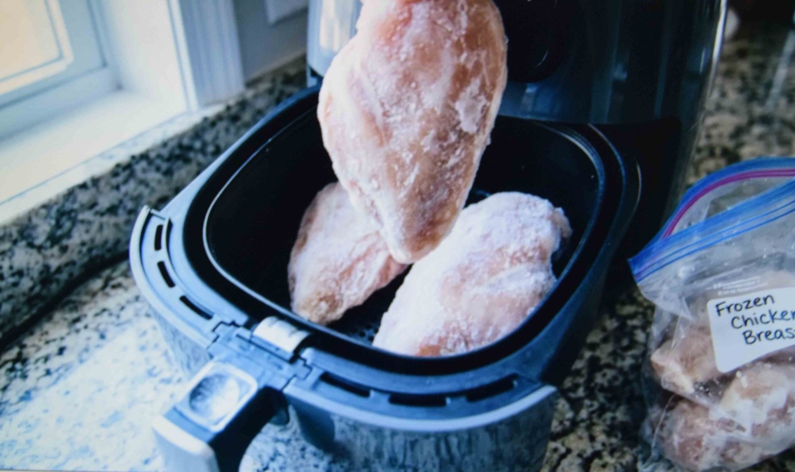 Frozen chicken breasts placed in the basket before any seasoning goes on