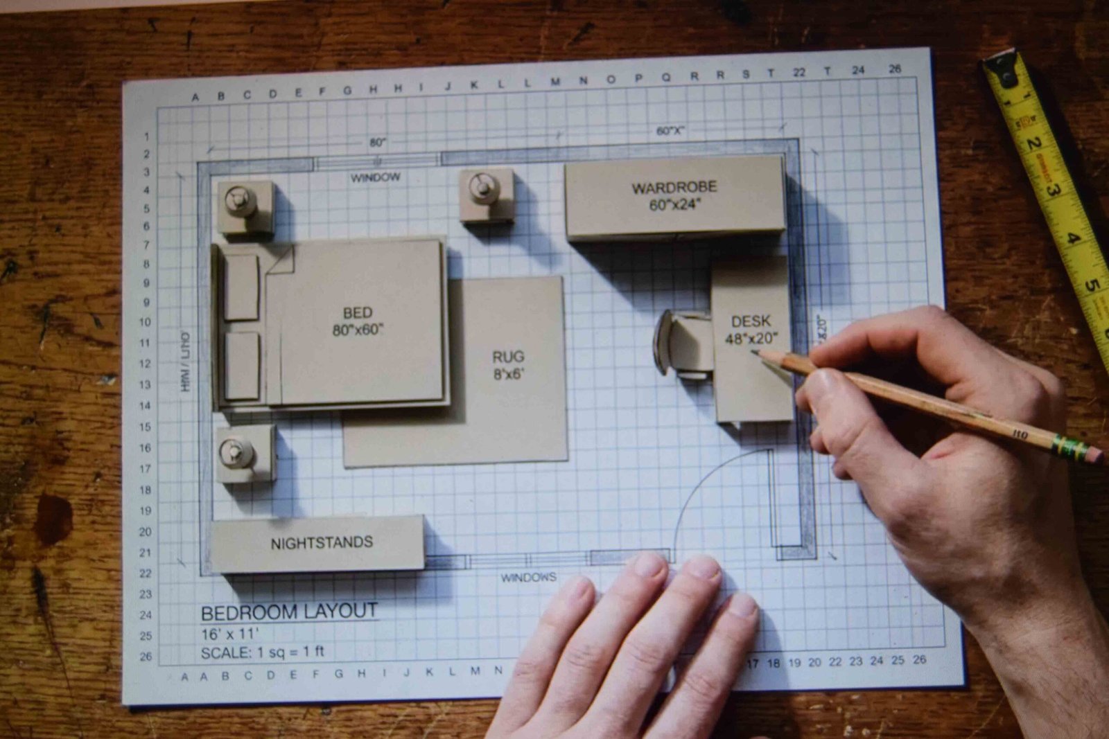 Paper cutouts on graph paper showing how to design a master bedroom before buying furniture