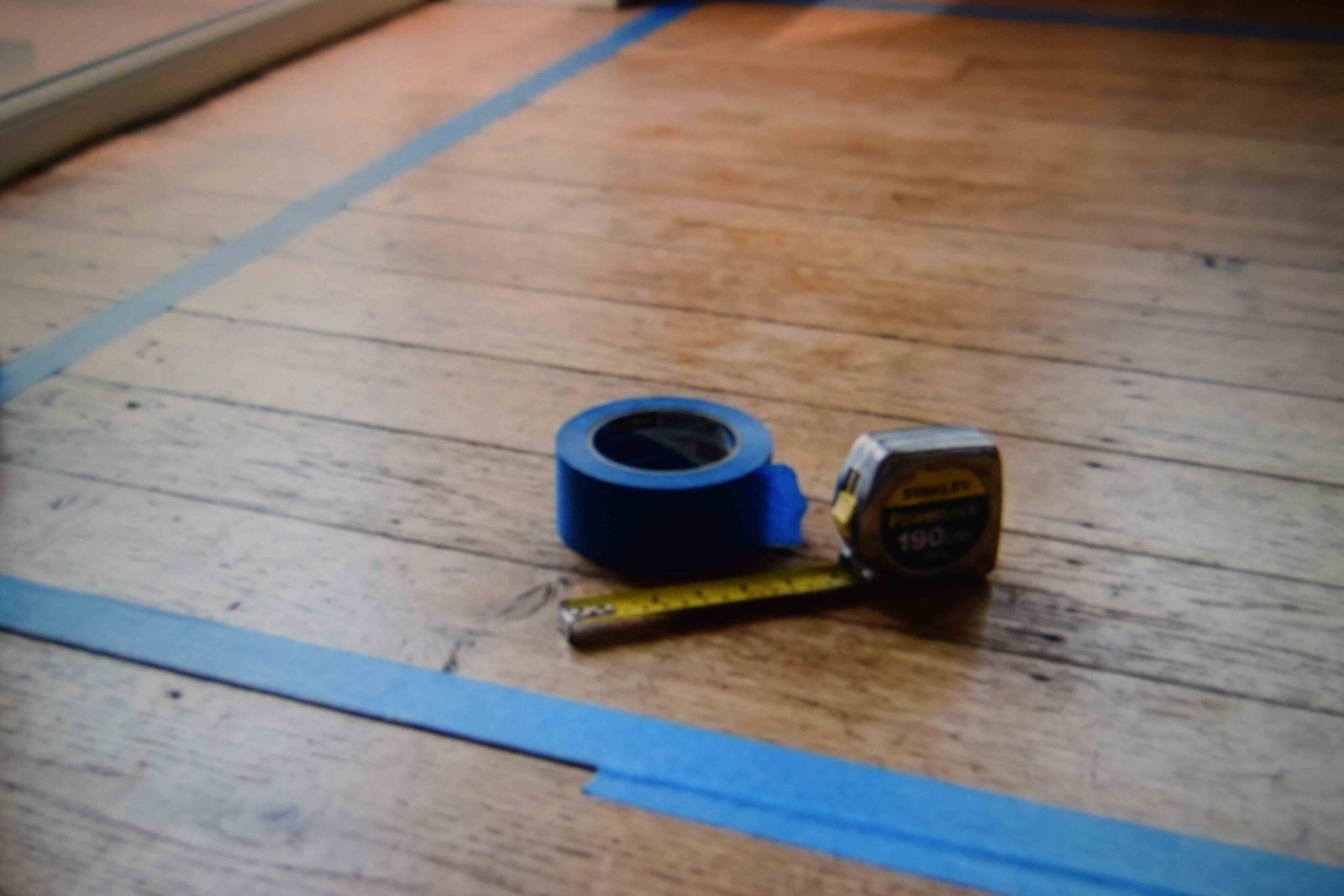 Painter's tape marking a bed footprint before ordering master bedroom furniture