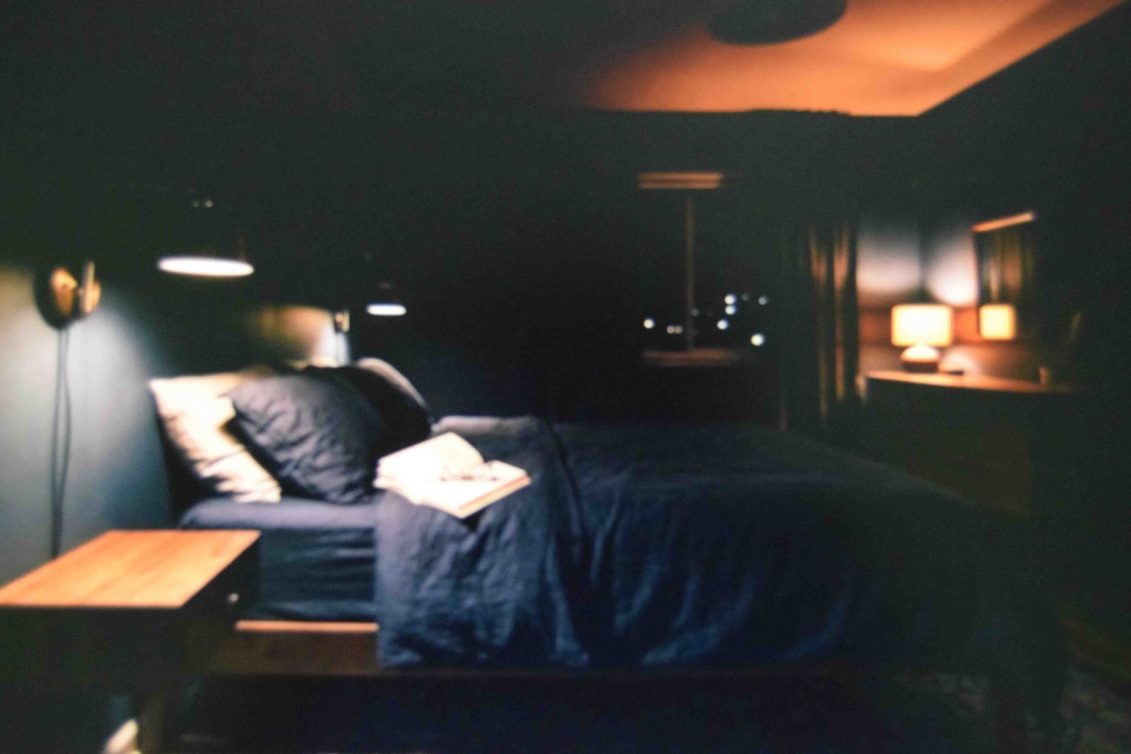 Wall mounted reading lamp and low bedside glow used as layered master bedroom lighting