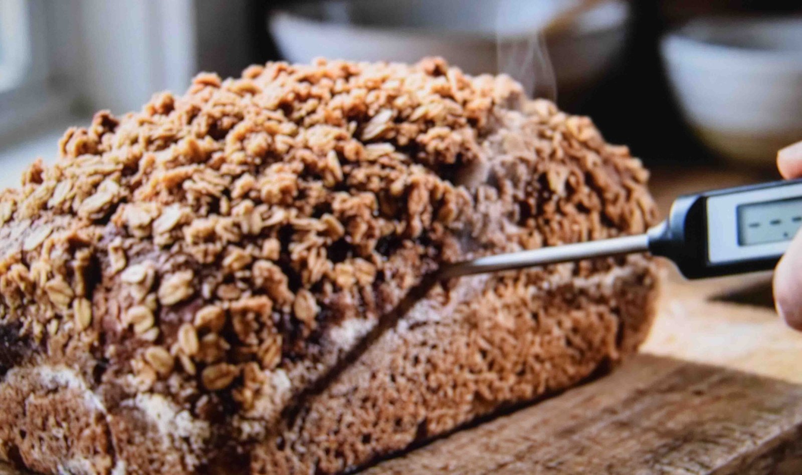 Checking pumpkin bread doneness with a thermometer through the side of the loaf