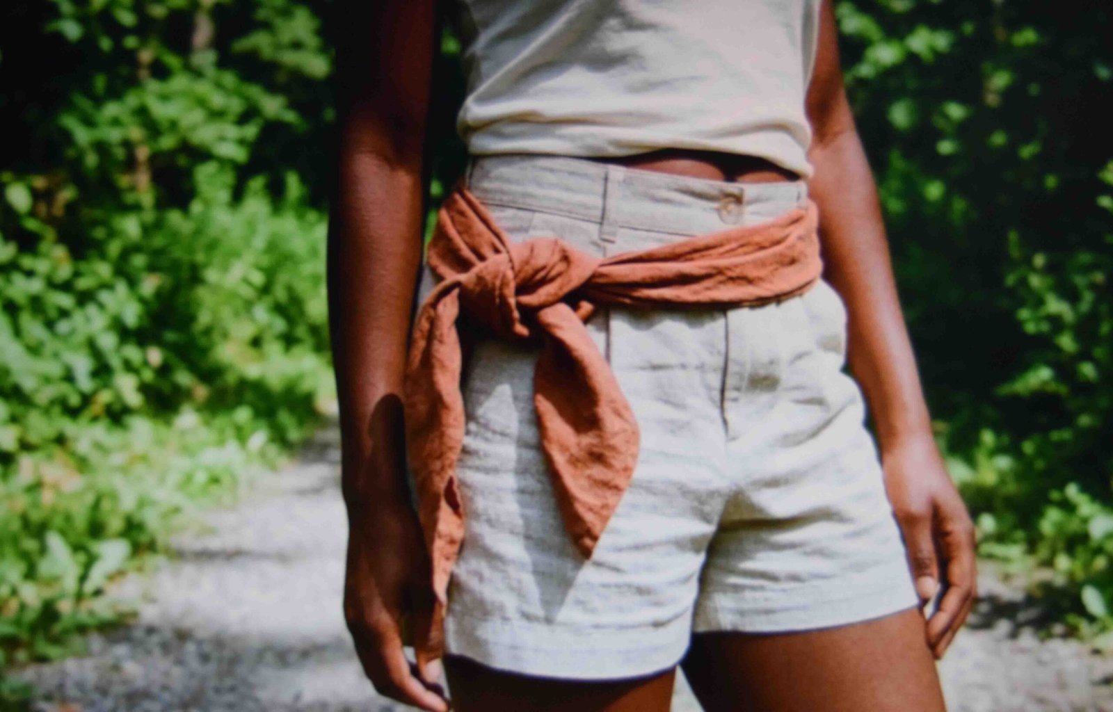 Linen scarf knotted loosely at the hip over a cotton tank in summer daylight