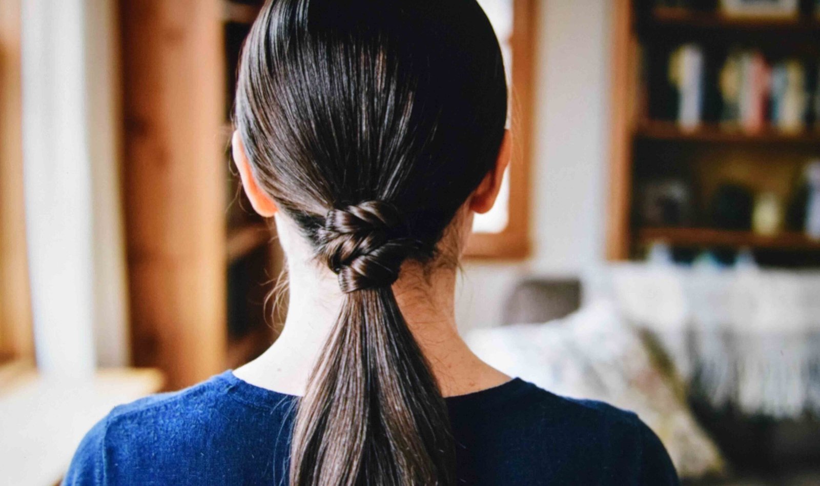 A low ponytail with twisted hair wrapped to hide the elastic completely
