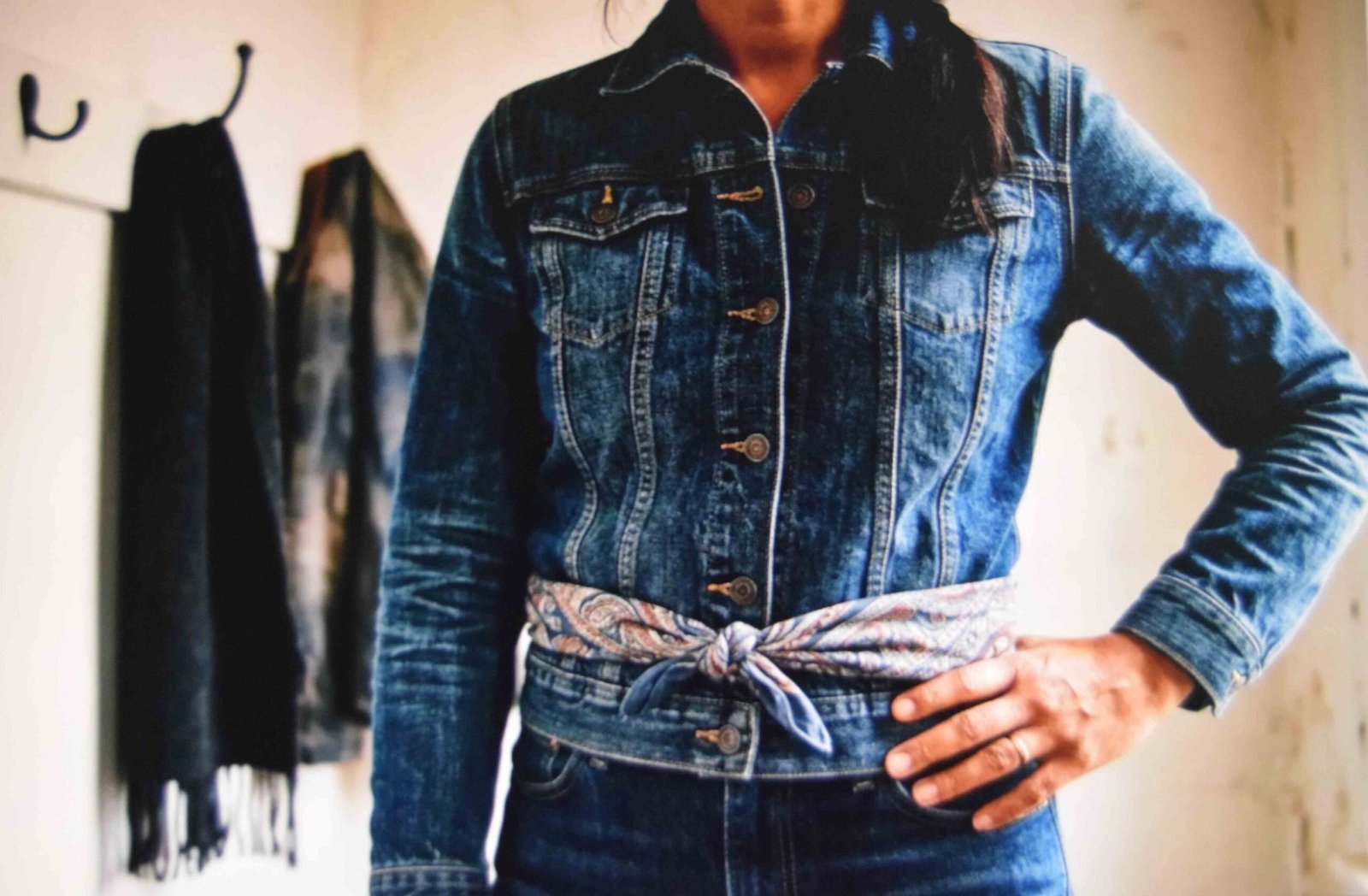 Scarf tied level with the hem of a buttoned denim jacket to mark the waist