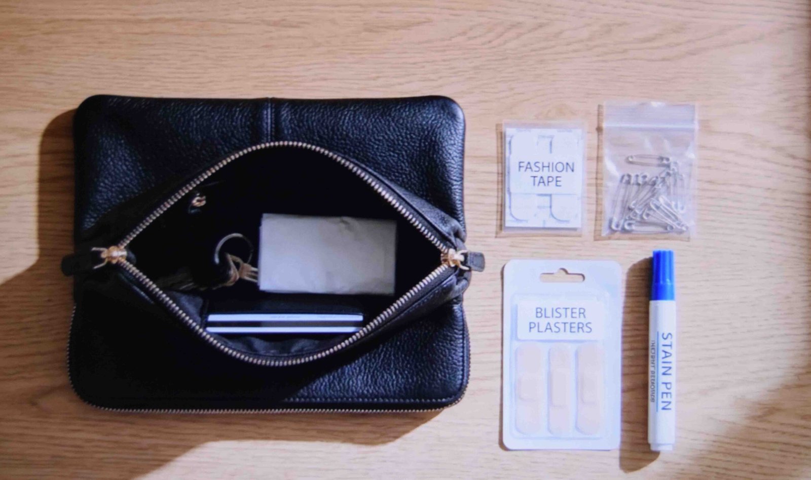 Tape pins plasters and a stain pen packed into a wedding guest clutch